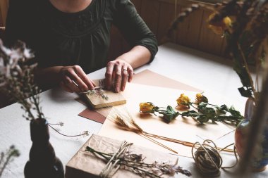 Kadınlar sıfır israf yapıyor, plastiksiz, moda el yapımı geri dönüşümlü kağıt ve masa örtülü kurutulmuş çiçeklerle hediye paketi yapıyor. Doğal Estetik.