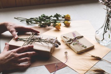 Kadınlar sıfır israf yapıyor, plastiksiz, moda el yapımı geri dönüşümlü kağıt ve masa örtülü kurutulmuş çiçeklerle hediye paketi yapıyor. Doğal estetik..