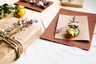 Samimi, sıfır atık, plastiksiz, modaya uygun el yapımı hediye kartı ve el yapımı geri dönüşümlü kağıttan yapılmış hediye kutusu ve masa örtülü kurutulmuş çiçekler. Doğal estetik..