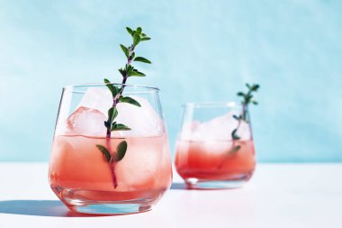 Yaz greyfurt kokteyli. Güneş ışığında sert gölgeli şifalı bitkilerle sağlıklı greyfurt içeceği. Mavi pastel arka planda palmiye yaprağı olan yaratıcı içecek..