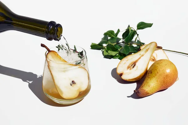 Çelik tepside armut, buz ve otlarla taze bir kokteyl. Bahçede ferahlatıcı içecek. Köpüklü şarap armut suyuyla bardağa dökülür..