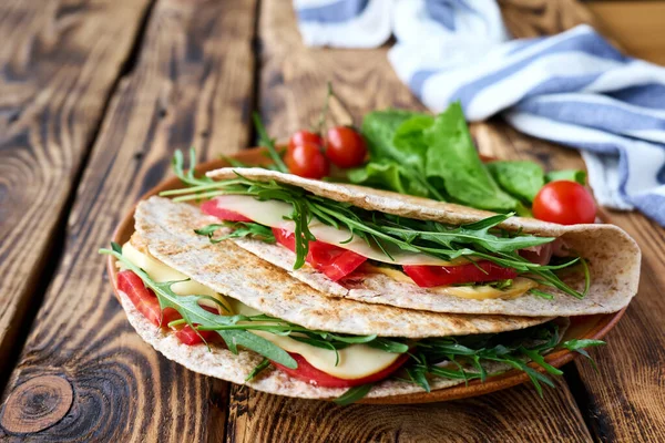 Mozzarella peynirli, domatesli, jambonlu ve roket salatalı Piadina Romagnola. İtalyan ekmeği ya da açık sandviç. Seçici odaklanma. Üst görünüm.