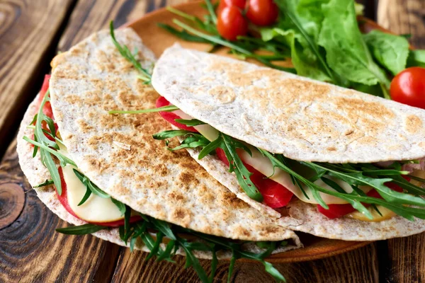 Mozzarella peynirli, domatesli, jambonlu ve roket salatalı Piadina Romagnola. İtalyan ekmeği ya da açık sandviç. Seçici odaklanma. Üst görünüm.