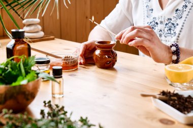 Kadın, masadaki aromaterapi seansını temel yağ dağıtıcı tıbbi bitkilerle, farklı yağ ve esanslarla hazırlıyor. Aromaterapi ve alternatif tıp konsepti. Doğal ilaçlar..
