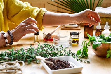 Kadın, masadaki aromaterapi seansını temel yağ dağıtıcı tıbbi bitkilerle, farklı yağ ve esanslarla hazırlıyor. Aromaterapi ve alternatif tıp konsepti. Doğal ilaçlar..