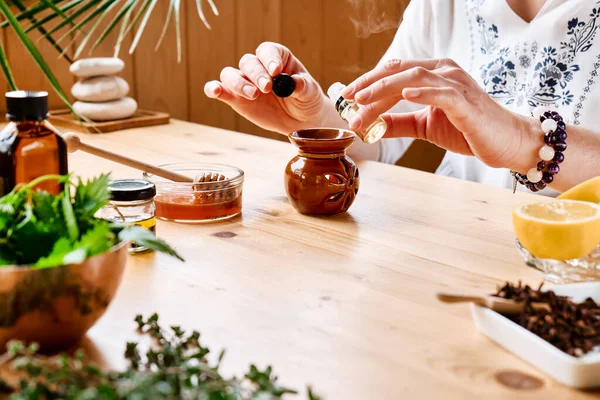 女士在餐桌上准备芳香疗法 配以药草 不同类型的香精油和香精油 芳香疗法和替代疗法的概念 自然补救办法 — 图库照片