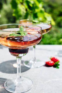 Taze yaz çilekli kokteyli ya da bahçedeki masada mocktail. Güneş ışığında gölgeli yaratıcı içecek..