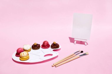 Sanat paletinde rengarenk badem kurabiyelerinin yaratıcı yaşamı. Asgari soyut kavram. Makarna badem ezmesi, pembe arka planda tatlı.