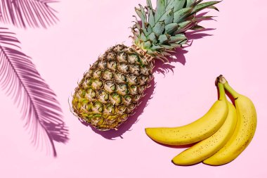 Yaz yaratıcı tropik fuit düzeni. Pembe pastel arka planda ananas ve muz ve palmiye yaprağı. Sağlıklı gıda yaz mevsimi konsepti. Üst Manzara. Boşluğu kopyala.