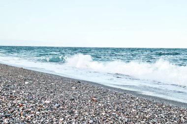Terkedilmiş çakıl taşı plajı, güverte sandalyeleri ve akşamları kapalı şemsiyeler. Sicilya turistik bir yer. Akdeniz 'de mevsim. İyon Denizi