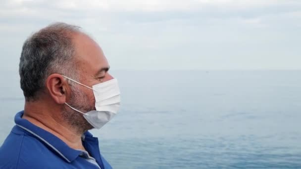 Muž si sundá ochrannou masku z obličeje a v letní den po skončení epidemie koronaviru se zhluboka nadechne na pláži u moře.. — Stock video