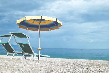 İki iskemle ve şemsiye çakıl taşı plajında. Sicilya turistik bir yer. Akdeniz 'de mevsim. İyon Denizi