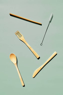 Açık yeşil pastel arka planda geometrik gölgeli çevre dostu bambu çatal bıçak seti. Sıfır atık, plastiksiz yaşam tarzı konsepti.