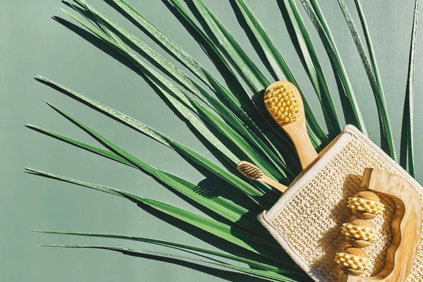 Waste-free bathroom accessories on light green background and palm leaf. Eco cosmetics products and tools. Zero waste, Plastic free. Sustainable lifestyle concept.