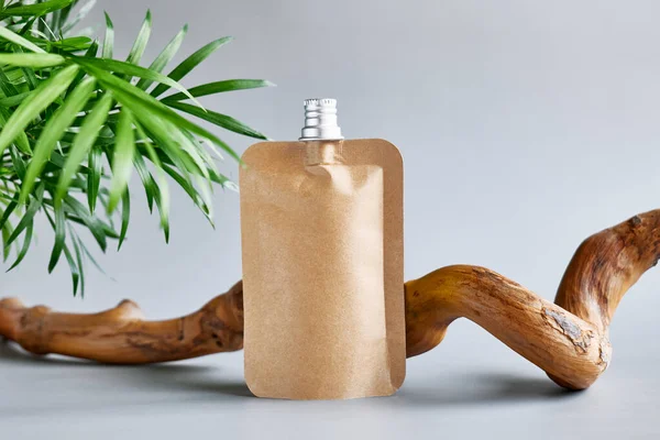 Pastel gri arka planda ahşap bir çıkmazın yanında geri dönüştürülmüş kağıt pakette krem. Ürün sunumu. Eko-biyoloji kozmetik konsepti. Kozmetik ya da güzellik ürünü tanıtım modası minimalist modelleme.