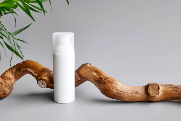 Pastel gri arka planda ahşap kapaklı beyaz krema tüpü. Kozmetik ürün reklamcılığı için sunum aşaması. Eko-biyoloji kozmetik konsepti. Güzellik ürünü tanıtım modası Minimalist modelleme.