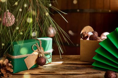 Noel kompozisyonu. Hediye kutuları ve tatil süsleri koyu ahşap masa üzerinde yeşil, altın ve kahverengi renkler. Sıcak kış tatili. Metin için boşluk.