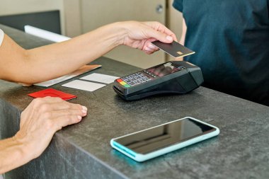 Kredi kartıyla ödeme yapan tanınmayan bir kadın işlemler için POS terminali kullanıyor.