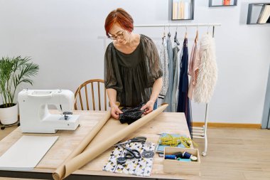 Moda kıyafetlerini butik atölyesinde paketleyen bayan tasarımcı, müşterinin çevrimiçi nakliye siparişini hazırlıyor