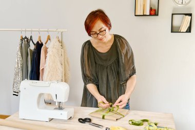 Moda kıyafetlerini butik atölyesinde paketleyen bayan tasarımcı, müşterinin çevrimiçi nakliye siparişini hazırlıyor