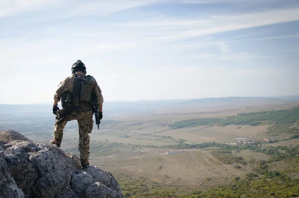 Un soldado con munición pesada en la roca — Foto de Stock