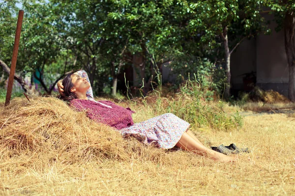 Jonge vrouw rusten op een hooiberg — Stockfoto