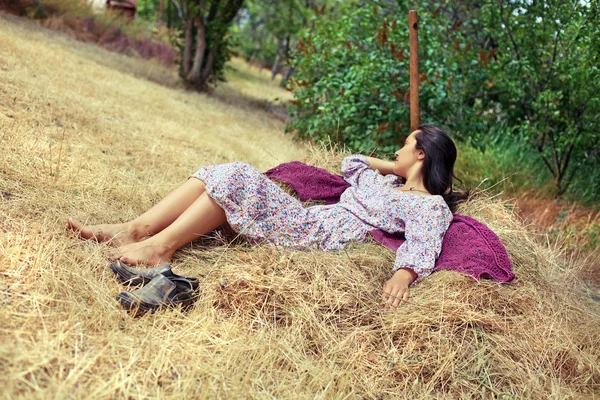 Jonge vrouw rusten op een hooiberg — Stockfoto