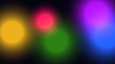 Yumuşak, odaktan uzak renkli daireler içeren büyüleyici bir hareket arkaplanı. Renk ışığı yavaşça hareket ediyor ve koyu siyah bir arkaplana çarpıyor..