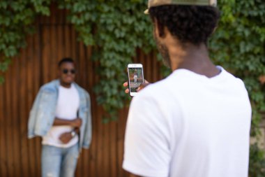 Afrikalı adam akıllı telefondan arkadaşını vuruyor.