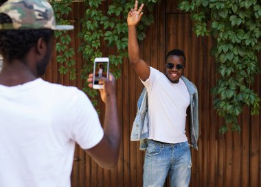 Afrikalı adam akıllı telefondan arkadaşını vuruyor.