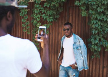 Afrikalı adam akıllı telefondan arkadaşını vuruyor.