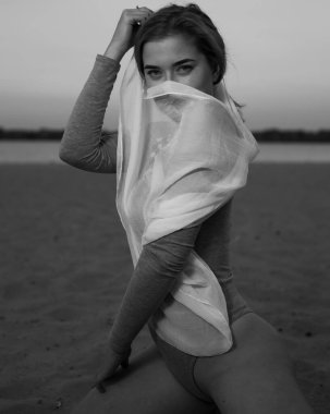 Gece kumsalında yeşil şalla poz veren şık bir kadın.