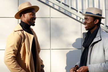 Afrikalı - Amerikalı erkekler, arkadaki tuğladan duvara karşı poz veriyorlar.