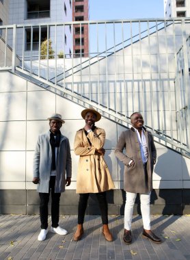 Afrikalı - Amerikalı erkekler, arkadaki tuğladan duvara karşı poz veriyorlar.