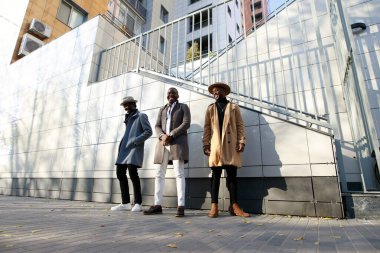 Afrikalı - Amerikalı erkekler, arkadaki tuğladan duvara karşı poz veriyorlar.