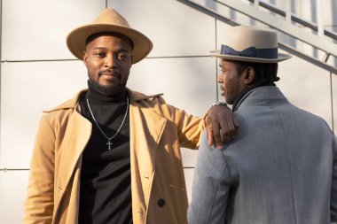 Afrikalı - Amerikalı erkekler, arkadaki tuğladan duvara karşı poz veriyorlar.