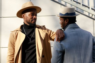 Afrikalı - Amerikalı erkekler, arkadaki tuğladan duvara karşı poz veriyorlar.