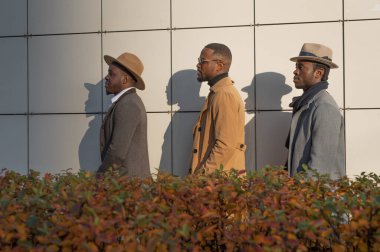 Afrikalı - Amerikalı erkekler, arkadaki tuğladan duvara karşı poz veriyorlar.