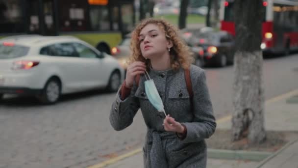 Mooie vrouw loopt door de stad en doet haar beschermend masker af — Stockvideo