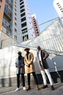 Afrikalı - Amerikalı erkekler, arkadaki tuğladan duvara karşı poz veriyorlar.