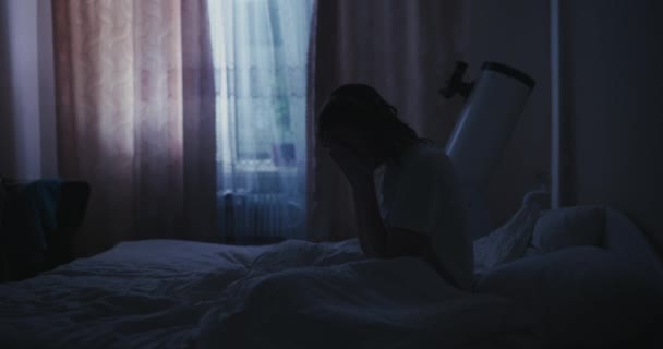 Una mujer se acuesta de noche en una cama y no puede dormir debido al insomnio. — Vídeo de stock