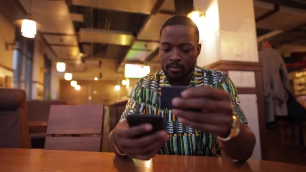 Homem afro-americano escreve número de cartão de crédito em smartphone, banco online — Vídeo de Stock