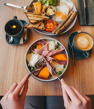 Kahvaltıyı çatal ve bıçakla yapan kadın.