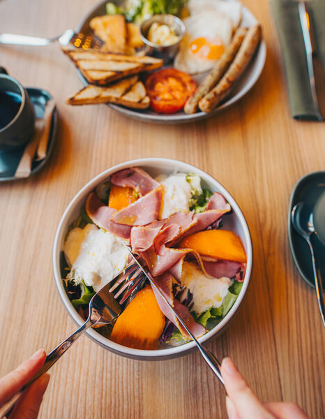 Woman eating breakfast with fork and knife