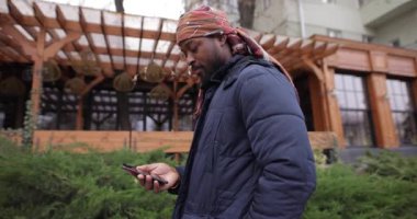 Şehir caddesinde cep telefonu kullanan Afrikalı Amerikalı bir adam.