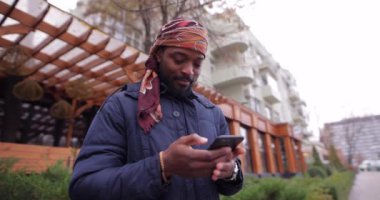 Şehir caddesinde cep telefonu kullanan Afrikalı Amerikalı bir adam.