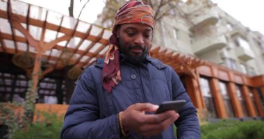 Şehir caddesinde cep telefonu kullanan Afrikalı Amerikalı bir adam.