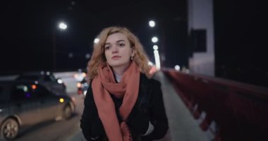 Hayalperest kadın gece köprüyü geçerken arabaların yanında düşüncelere dalıyor.