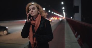 Akıllı telefonlu bir kız otoyolda yürüyor.