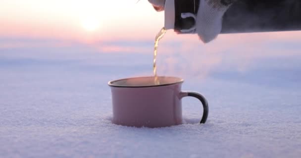Giet thee uit een thermoskan in een kopje op een besneeuwde dag — Stockvideo